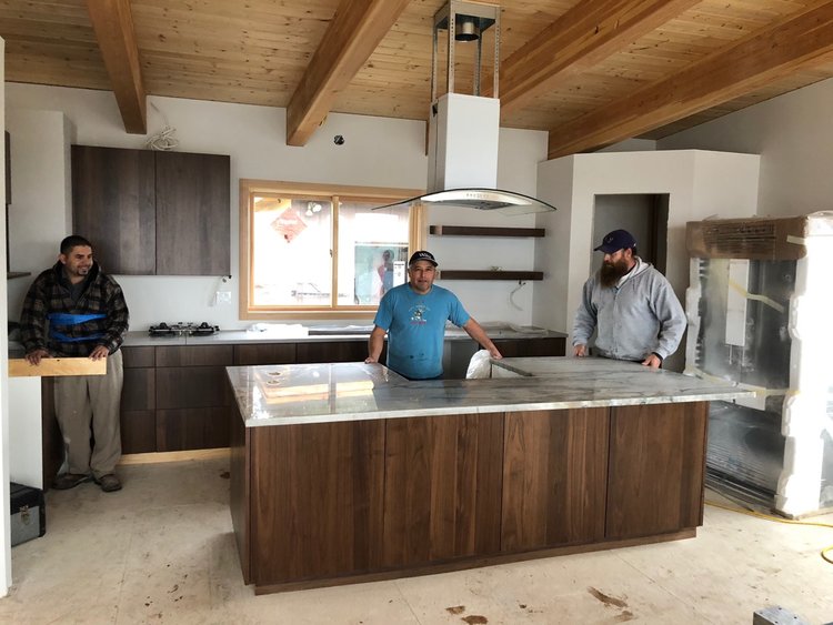 Three countertop installers from Tops Countertops setting up a large granite island in a modern South Sound kitchen.